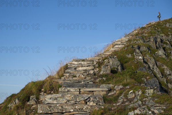 Woman with hiking poles walking up Rørsethornet stone stairs, with 3292 steps one of the longest