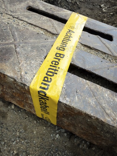 Flapping tape with the indication of an installed fibre optic cable at a construction site in