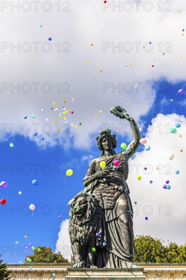 Colourful balloons rise high above the statue of Bavaria into the white-blue sky, grand finale of