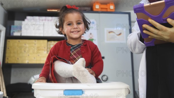 A doctor examining a refugee child for malnutrition in the camp using weight and height measurement