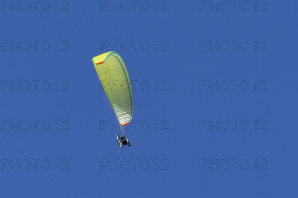 Paraglider flying in a blue sky, England, United Kingdom