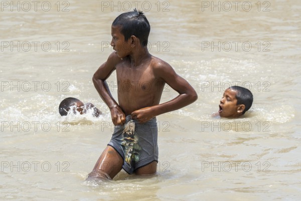 Children bathe in the Brahmaputra River to seek relief from the intense summer heat in Guwahati,