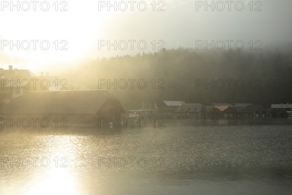 Mystical morning at Königssee in Schönau with boathouses. Sunrise and beautiful wafts of mist over