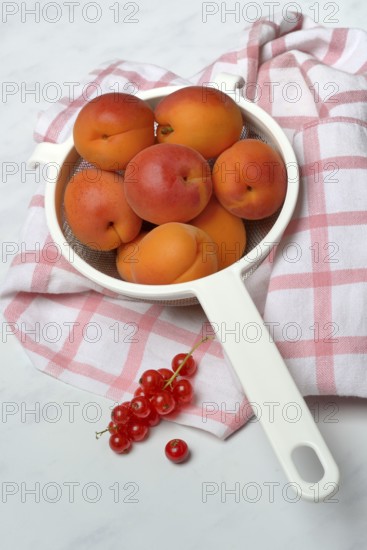 Apricots in a colander and redcurrants