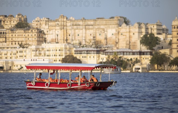 Excursion boat on Lake Pichola, behind the City Palace in the evening light, Udaipur, Rajasthan,
