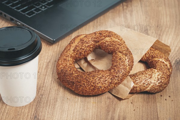 Simits with coffee on a wooden table, with a laptop, in a cozy working environment, snack,