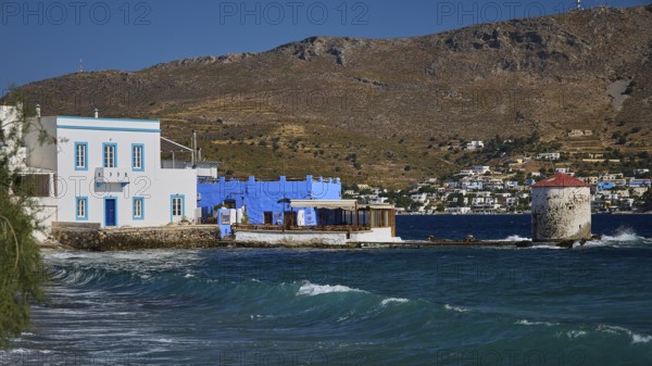 Windmill on the coast with blue and white architecture and undulating sea in the background, Agia