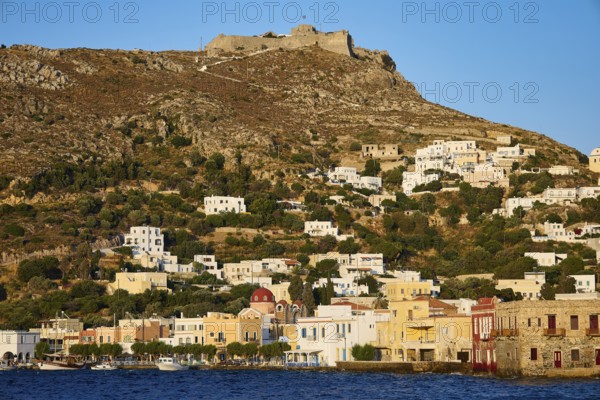 Panteli Fortress, White-blue houses on a hill with an old fortress above, coast in the foreground,