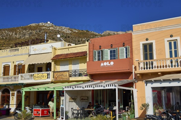 Colourful shops and cafés along a shopping street under a bright blue sky, Agia Marina, Leros,