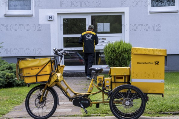 Postman, Deutsche Post, distributes the mail in an apartment building, electric tricycle, North