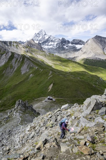 Mountaineer on hiking trail, Glorerhütte mountain hut and mountain peak in the background, Wiener