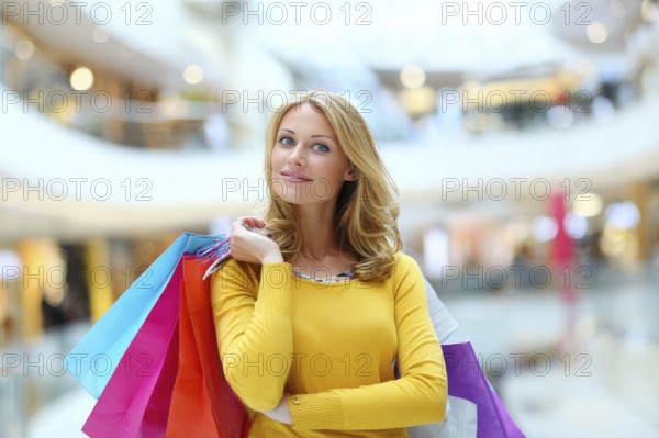 Beautiful young happy attractive woman with bags of different colours in shopping center mall