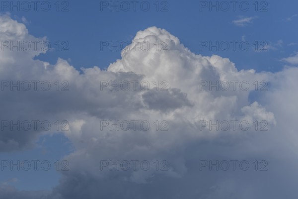 Dark storm clouds gather in the sky over a vast rural landscape, signalling an impending summer