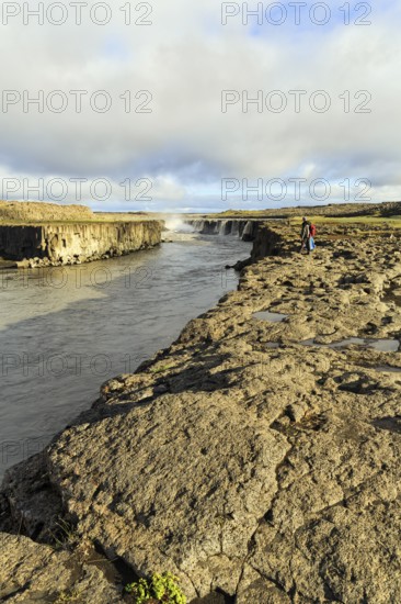 Hikers at the river Jökulsa a Fjöllum, canyon, waterfall Selfoss on the horizon, North Iceland,
