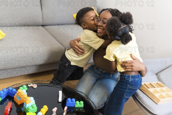Loving mother enjoying a tender moment with her kids, receiving hugs and kisses in their cozy