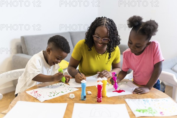 Happy african american family enjoying creative activities at home, painting colorful pictures with
