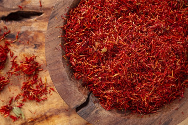 Spice saffron threads, in a wooden bowl, on a wooden table, top view, close-up
