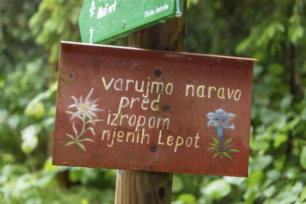 Sign with Slovenian text in front of a green, natural backdrop, Zgornje Jezersko, Gorenjska,