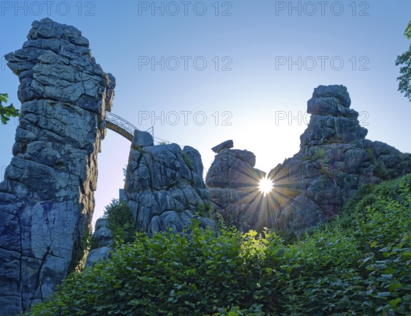 The morning sun shines through an opening in the Externsteine. The Externsteine, a sandstone rock