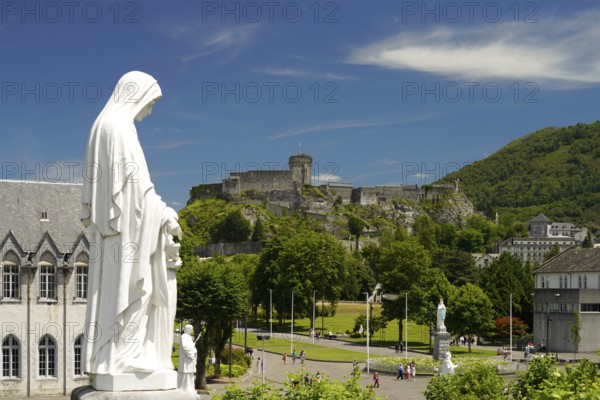 Statue on Rosary Square and the Château fort de Lourdes fortress in the Marian pilgrimage town of