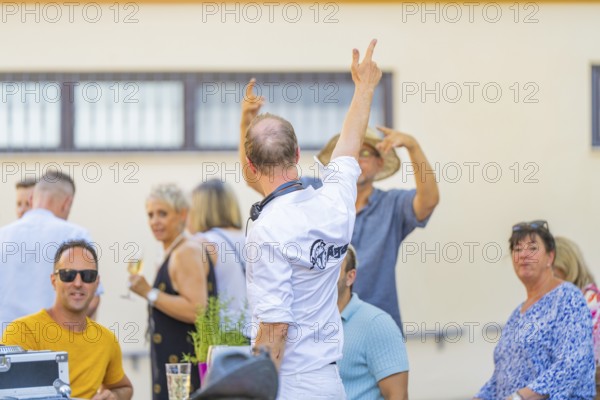 People enjoying themselves outdoors at a social event with a summery atmosphere, 950 years Weil der