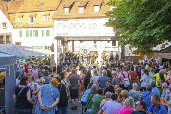 A large crowd gathers around a stage during a concert at a town festival, 950 years Weil der Stadt