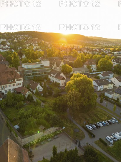 Landscape with a village car park at sunset, surrounded by trees and a quiet atmosphere, 950 years