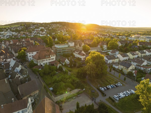 Sunset over a village with car parks, surrounded by lush nature and peaceful countryside, 950 years