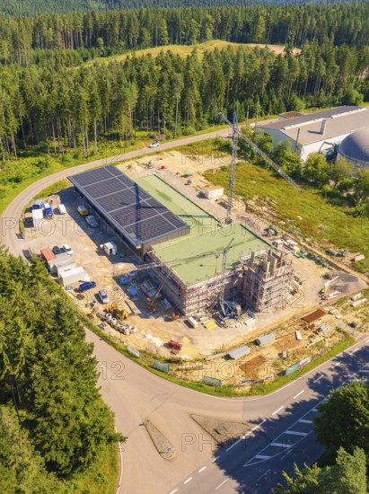 Building complex under construction near the forest, with solar panels and a crane visible, new