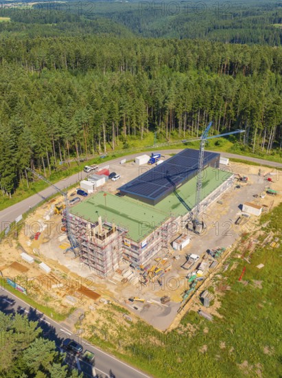 A building with solar panels and a crane in a wooded industrial area, new fire station building,