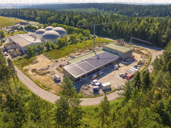 Embedded in a forest landscape, the picture shows solar systems on buildings at a construction