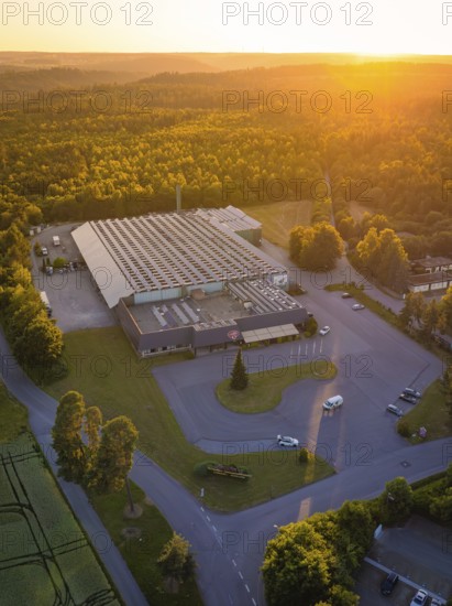 Factory building from the air at sunset, surrounded by woods and roads, Schnaufer sparkling wine