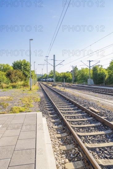 View along the railway tracks in a green environment, clear sky, feeling of travelling, Weil der