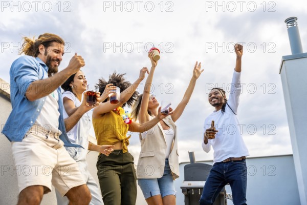 Cheerful multi ethnic friends dancing and enjoying drinks while having a fantastic time at a