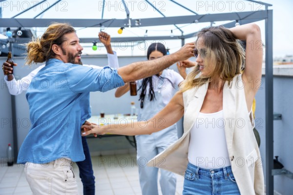 Cheerful young people dancing and having fun at a rooftop party, celebrating friendship and