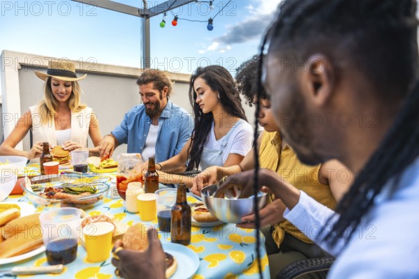 Multi ethnic friends enjoying a lively barbecue party on an urban rooftop, savoring delicious