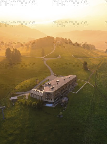 Large building on a hill at sunset in a peaceful mountain landscape, Alpe di Siusi, Dolomites,