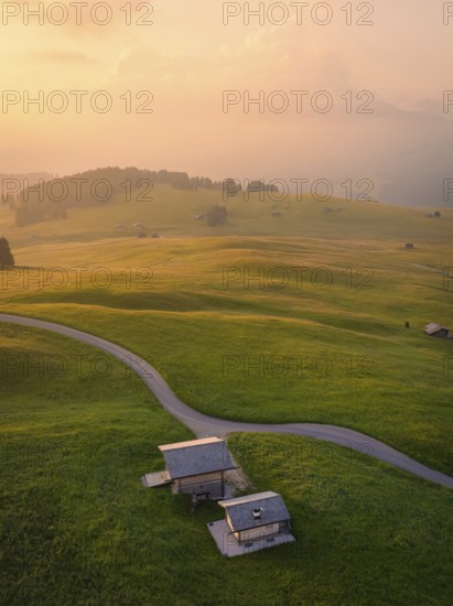 Houses and streets in a hilly landscape in warm evening light, Alpe di Siusi, Dolomites, South