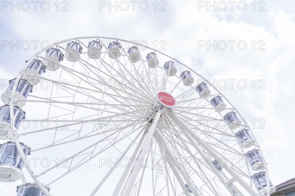 Modern Ferris wheel with gondolas in front of a slightly cloudy sky, Ferris wheel construction,