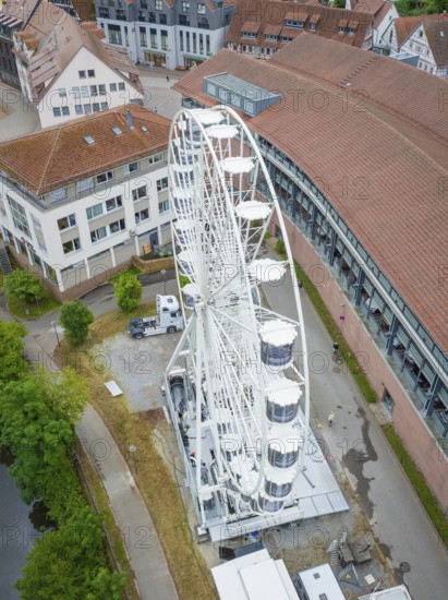 Close-up of a white Ferris wheel in an urban area with several buildings and a river, Ferris wheel