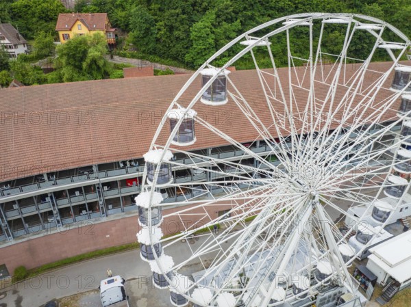 Close-up of the Ferris wheel with detailed view of the cabins and buildings in the background,
