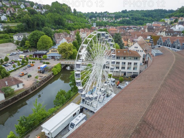 Aerial view of a Ferris wheel in the middle of a town in summer weather and wooded surroundings,