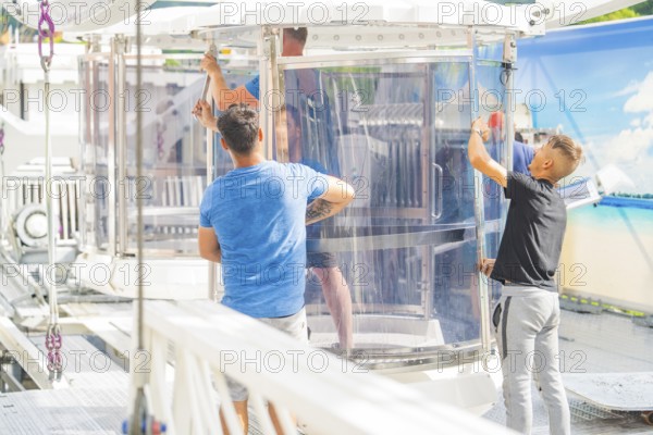 People working on a glass cabin of a Ferris wheel in an amusement park, Ferris wheel construction