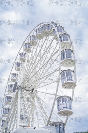 Ferris wheel with numerous gondolas in front of a cloudy sky, Ferris wheel construction for the