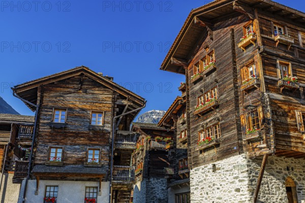 Old wooden houses in log construction, decorated with flowers, historic village centre, Grimentz,