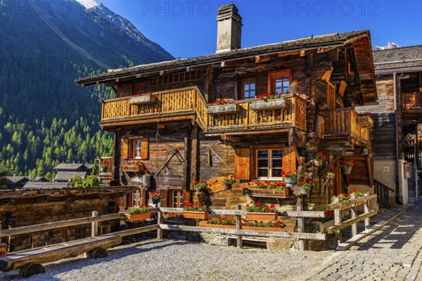 Old wooden house in log construction, decorated with flowers, historic village centre, Grimentz,