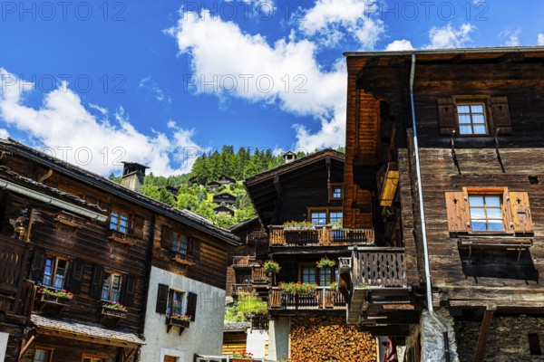 Old wooden houses in log construction, decorated with flowers, historic village centre, Grimentz,