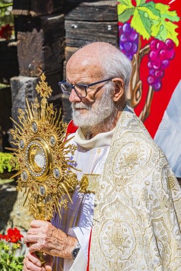 The priest with the golden monstrance during the Corpus Christi procession, historic village