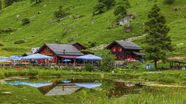 Huts and parasols reflected in the pond, Relais Tzoucdana, Zinal, Val d'Anniviers, Valais Alps,