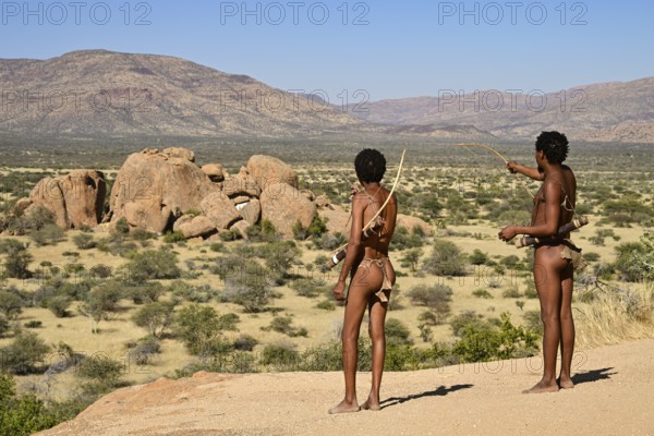 Two Bushmen with bows and arrows overlooking the landscape from a rocky hill, Erongo Mountains,